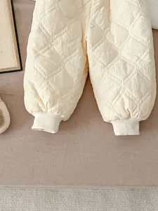 Quilted toddler cotton pants detail, soft beige winter warm trousers with ribbed cuffs.