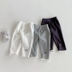 Detailed shot of infant ribbed leggings with lace trim and bow embroidery in multiple colors.