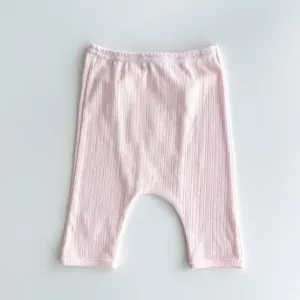 Infant ribbed knit pants detail, cute pink baby leggings close up, soft texture fabric.