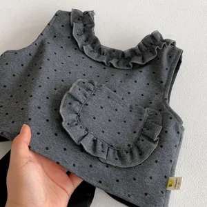 Girls cute dark grey sleeveless top with polka dots, ruffled collar and pocket detail for kids.