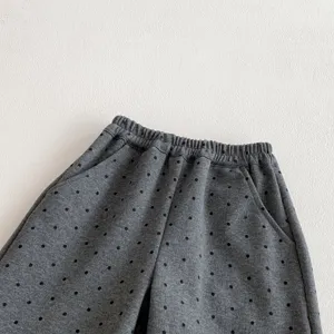 Girls grey polka dot trousers detail view, featuring elastic waist and convenient pockets.