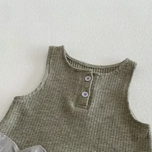 Infant waffle knit sleeveless baby top detail shot, soft comfortable cotton material.