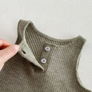 Close-up detail of infant waffle knit sleeveless vest top showing buttons and fabric.