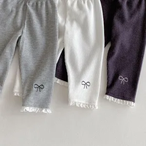 Detailed view of toddler ribbed knit leggings featuring delicate lace cuffs and cute bow embroidery.