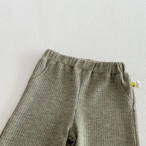 Infant waffle knit pants detail view, soft cotton baby trousers with elastic waist in green.