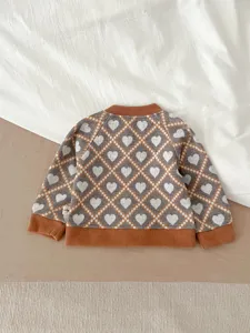 Vue détaillée du gilet en tricot pour bébé avec motif losanges cœurs et bords côtelés.