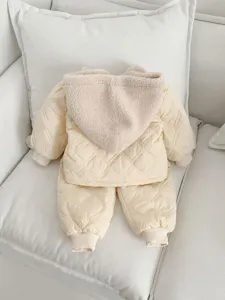 Close-up detail of infant winter warm quilted hooded jacket and pants set in soft beige color.