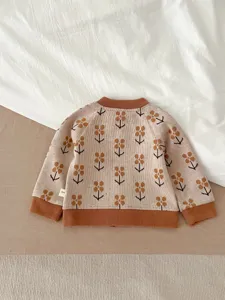 Gros plan sur le gilet en tricot pour bébé avec motif floral et finitions côtelées.