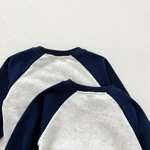 Vista dettagliata della felpa raglan per bambini con blocco di colore e tessuto morbido.