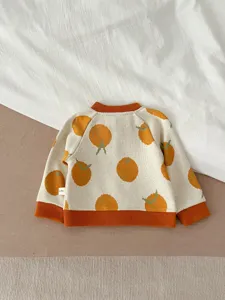 Détail de pull en tricot pour bébé avec motif orange, col et poignets côtelés, joli vêtement mignon.