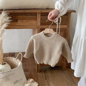 Detalle jersey bebe de punto, cuello redondo liso manga larga en un suave tono beige.