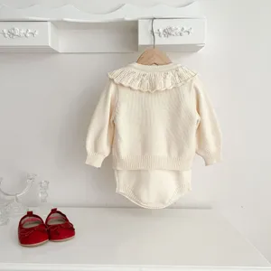 Detail view of baby knit cardigan and romper set in beige with delicate lace collar, soft cotton.