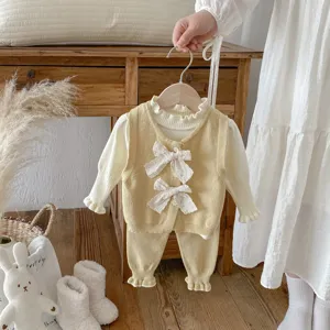Dettaglio gilet in maglia per bimbi con fiocchi di pizzo e set pantaloni coordinati.