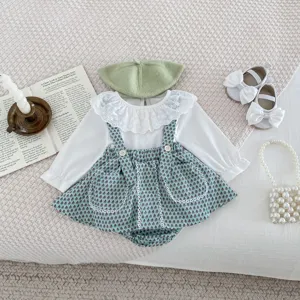 Detailed flat lay of cute baby girl outfit set including floral overall dress, top and hat.