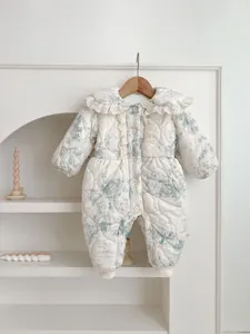 Cozy quilted baby romper detail showcasing floral print, elegant ruffled collar and wooden buttons.