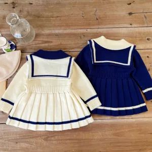 Detailed view of cute baby girls sailor style knit sweater dress, long sleeve pleated skirt.