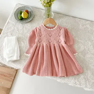 Pink baby knitted dress detail shot with hollow-out diamond and lovely lace collar, cozy setup.