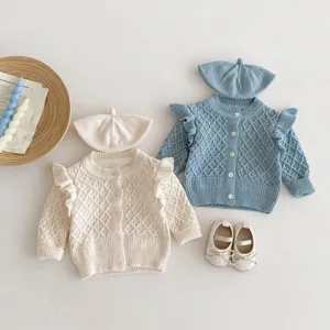 Infant knit cardigan detail shot showcasing diamond jacquard pattern, ruffles and matching hat.