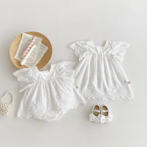 Detailed flat lay of cute white cotton baby lace flutter sleeve dress, romper and shoes.