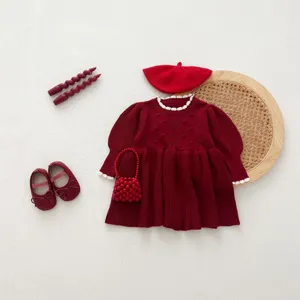 Details of a charming red knit baby dress flat lay with matching beret, shoes and bag.