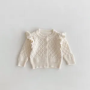 Infant knit cardigan close-up, diamond jacquard pattern, ruffle sleeve detail, soft texture.