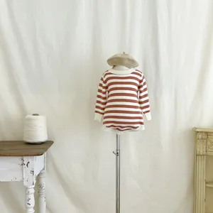 Detailansicht des gestreiften Baby-Stramplers mit Baret auf Puppe im gemütlichen Studio.