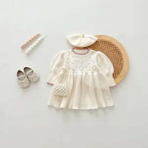 Exquisite knit baby dress detail featuring delicate diamond patterns and cute pearl bag accessory.