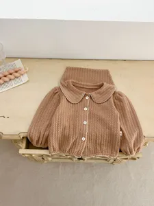 Detalle de cárdigan para bebé, cuello en contraste con delicado encaje y botones.