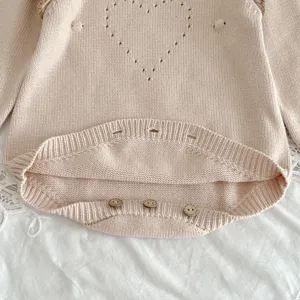 Süßes Baby Strick Strampler Detail, zartrosa Säugling Cardigan mit Herz und Holzknöpfen.