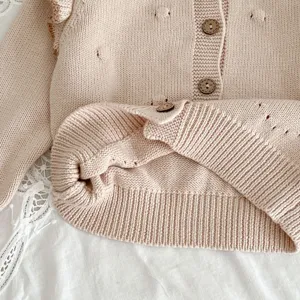 Baby Mädchen Strickjacke Detailansicht, rosa Pullover mit Knöpfen und strukturierten Noppen.