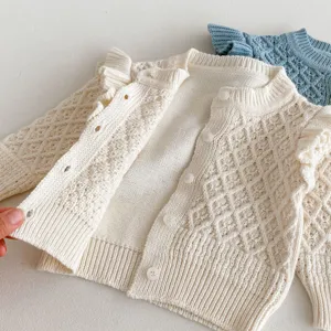 Close-up detail view of the baby knit cardigan, showing fine diamond jacquard texture and buttons.