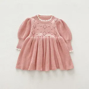 Pink baby girl knit dress with long puff sleeves and cute diamond pattern. Infant autumn.
