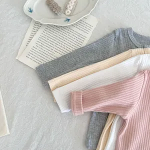 Detailed close-up shot of soft cotton ribbed baby long-sleeve t-shirts in pastel colors.