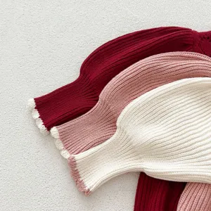 Detailed view of kids knit dress sleeves in burgundy pink and white colors with ribbed texture.