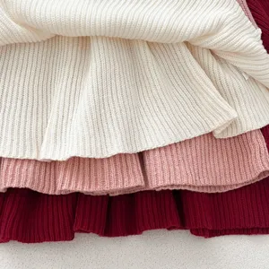 Detailed shot of layered knit baby girl dress in white pink and burgundy colors soft ribbed fabric