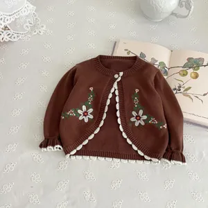 Detailed view of baby girl brown knit cardigan with lovely white floral embroidery and lace.