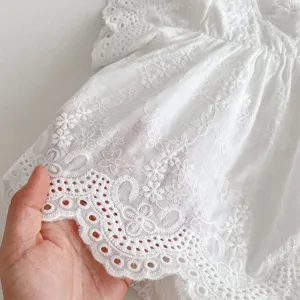Baby girl white cotton lace romper detail view showing delicate soft fabric texture.