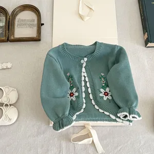 Detailed view of baby girl green knit cardigan featuring delicate floral embroidery and ruffles.