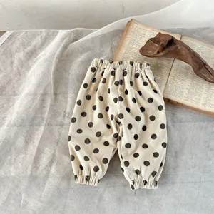 Dettaglio di pantaloni in velluto a coste per neonati, beige con pois neri ed elastico.