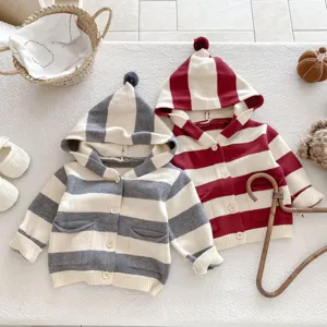 Detailaufnahme der Babystrickjacke mit Kapuze, weicher gestreifter Pullover mit Bommel.