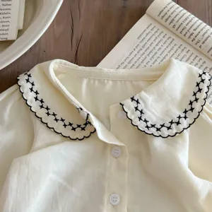 Babypflege Baumwollbluse mit schwarzem bestickten Kragen und Knöpfen für den Herbst.