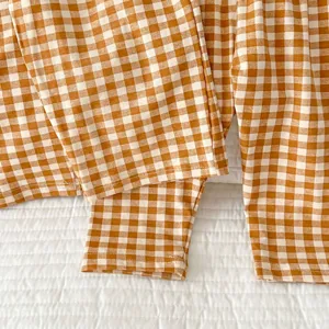 Close-up detail of infant cotton checkered pants and clothing, showing soft brown gingham pattern.