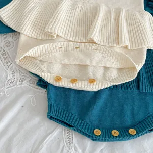 Detail of cute knit baby romper, soft texture, ruffles and wooden buttons for infant girls.