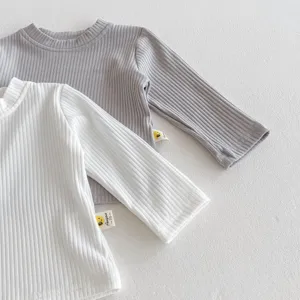 Nahaufnahme von Baby Rippstrick Langarmshirts in Weiß und Grau mit süßen Seitenetiketten.