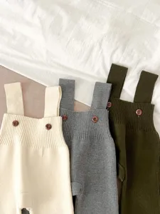 Detailed view of baby knit strap pants featuring three neutral colors and cute wooden buttons.
