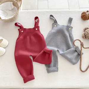 Detailaufnahme kuscheliger Baby-Latzhosen aus Strick in Rot und Grau mit süßen Knöpfen und Stoff.