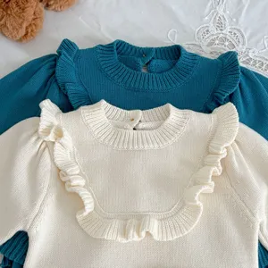 Detail shot of infant knitted rompers featuring elegant ruffles and soft cotton fabric texture.