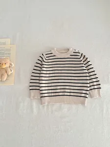 Detailed view of a cute baby striped knit sweater in beige and black, soft and cozy pullover style.