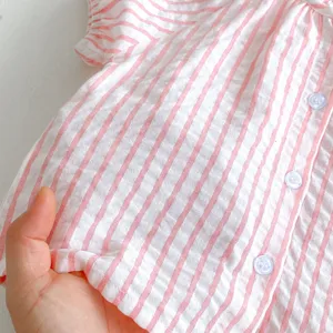Close-up view of pink and white striped baby shirt fabric, showing soft texture and buttons.