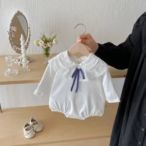 Detail view of white baby long sleeve romper featuring delicate lace collar and blue bow.